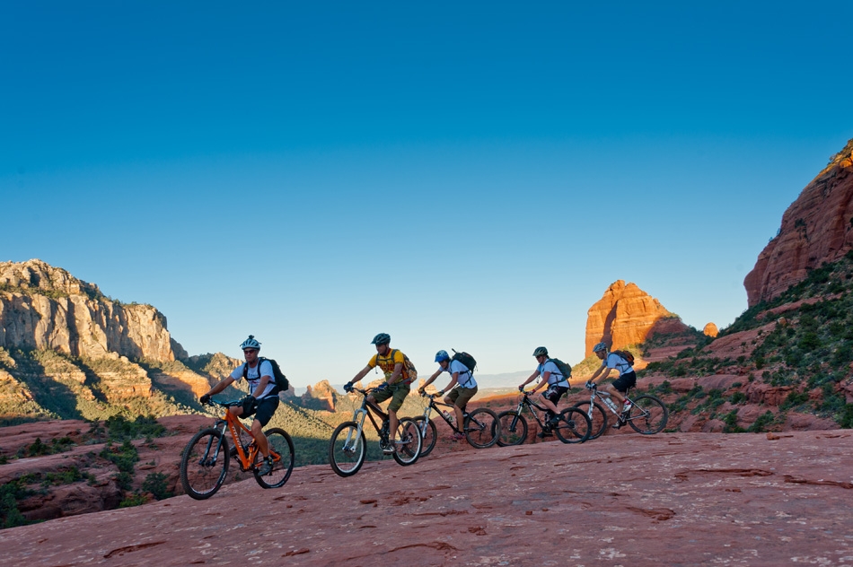 Five mountain bikers riding the valley between mountains