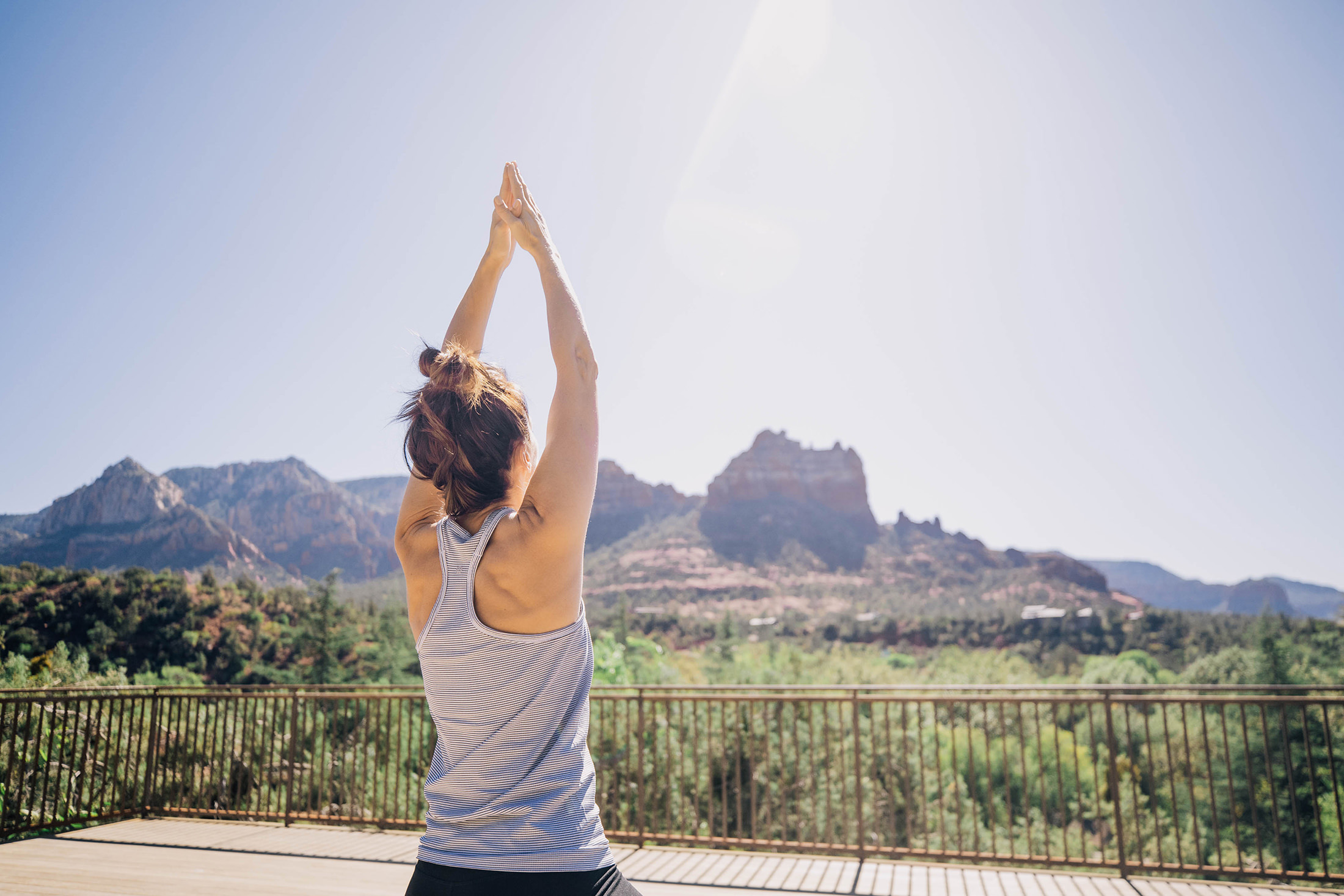 A woman practicing yoga outside looking out at the tall mesas in the distance